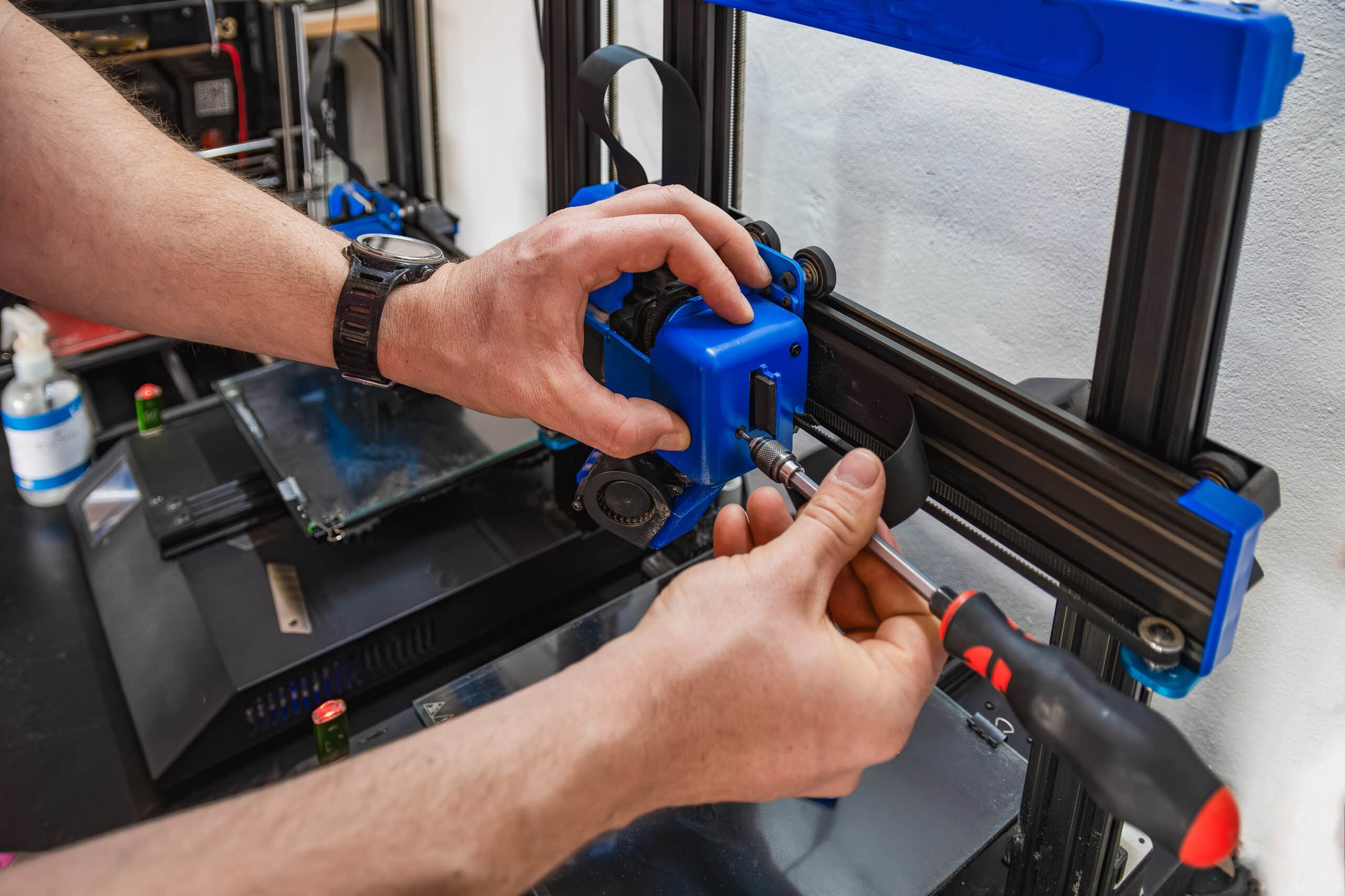 Close-up of a technician's hands performing maintenance on a 3D printer
