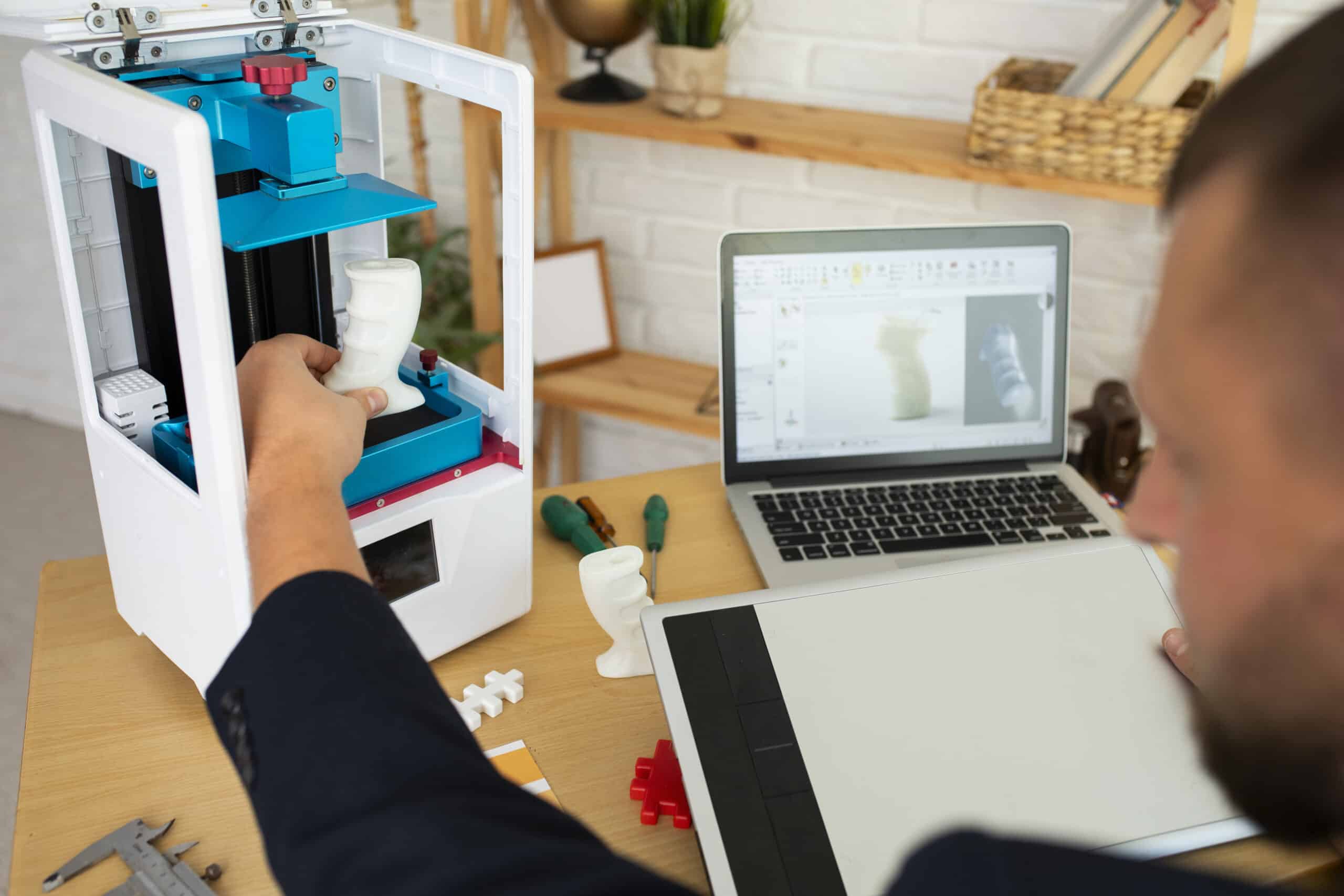 Person checking a desktop 3D printer's display during troubleshooting