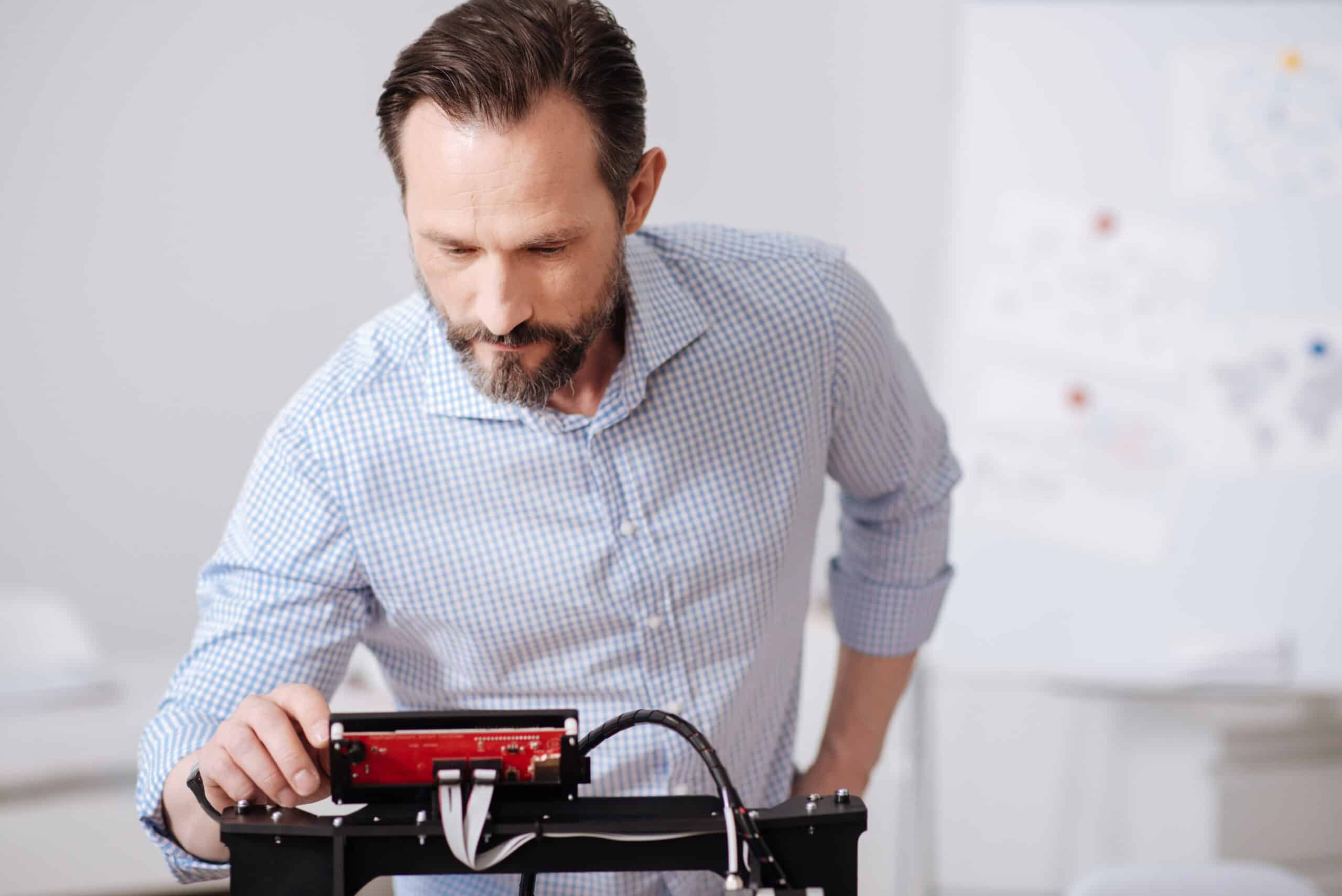 Person closely inspecting a 3D printer's control screen, illustrating printer error troubleshooting