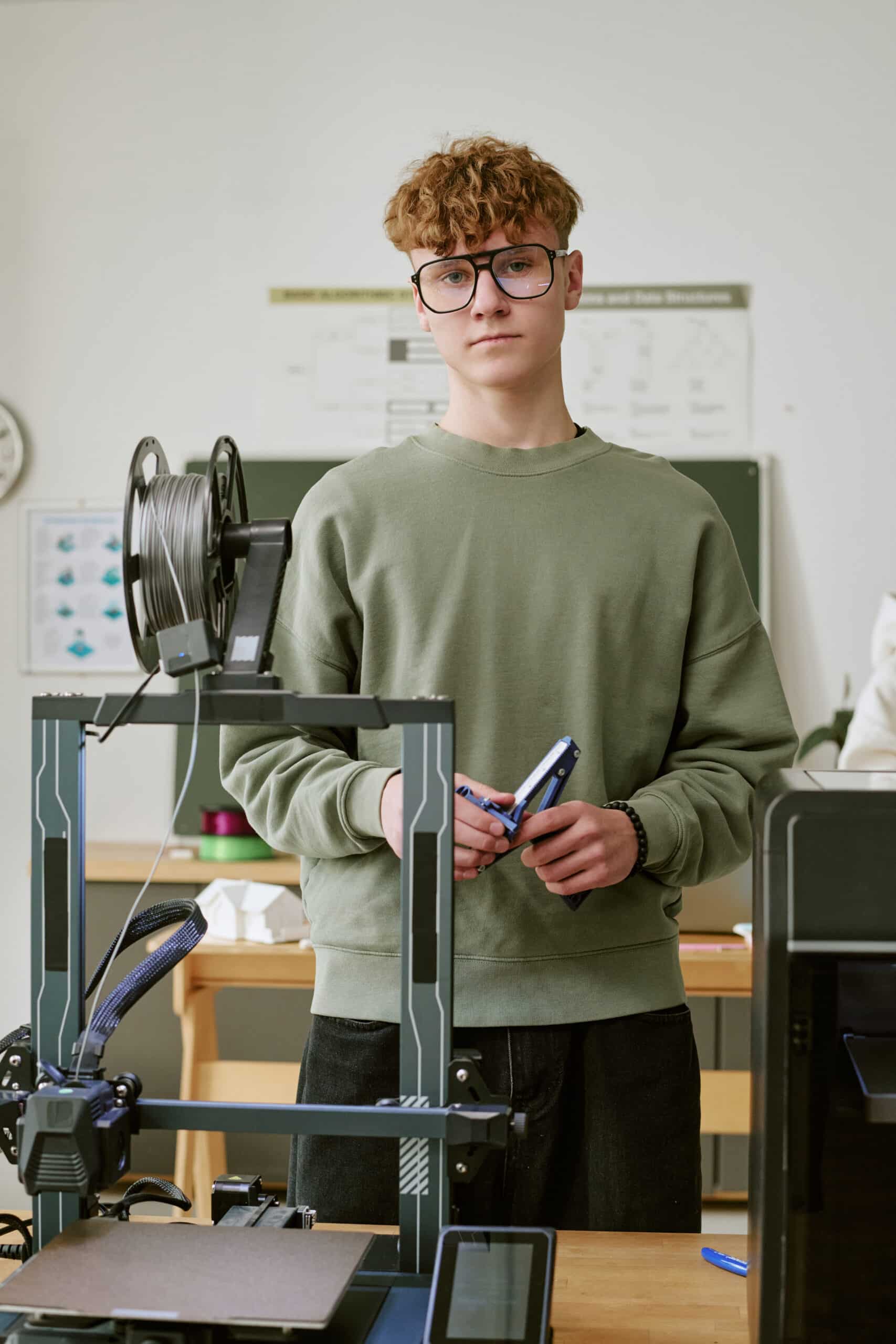 Teenage boy using a 3D printer in a school workshop