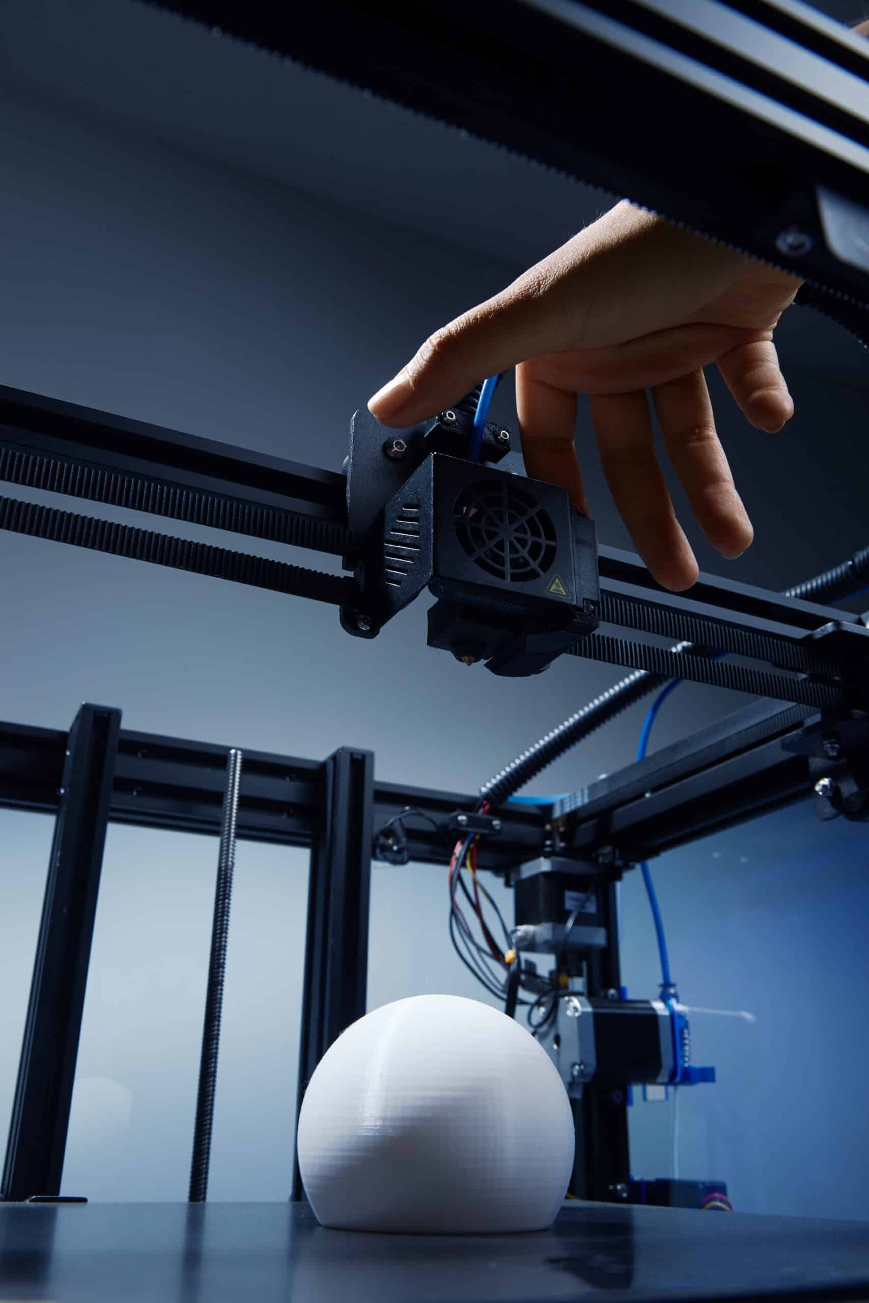 Hand adjusting settings on a desktop 3D printer's control panel, relevant to troubleshooting and error handling