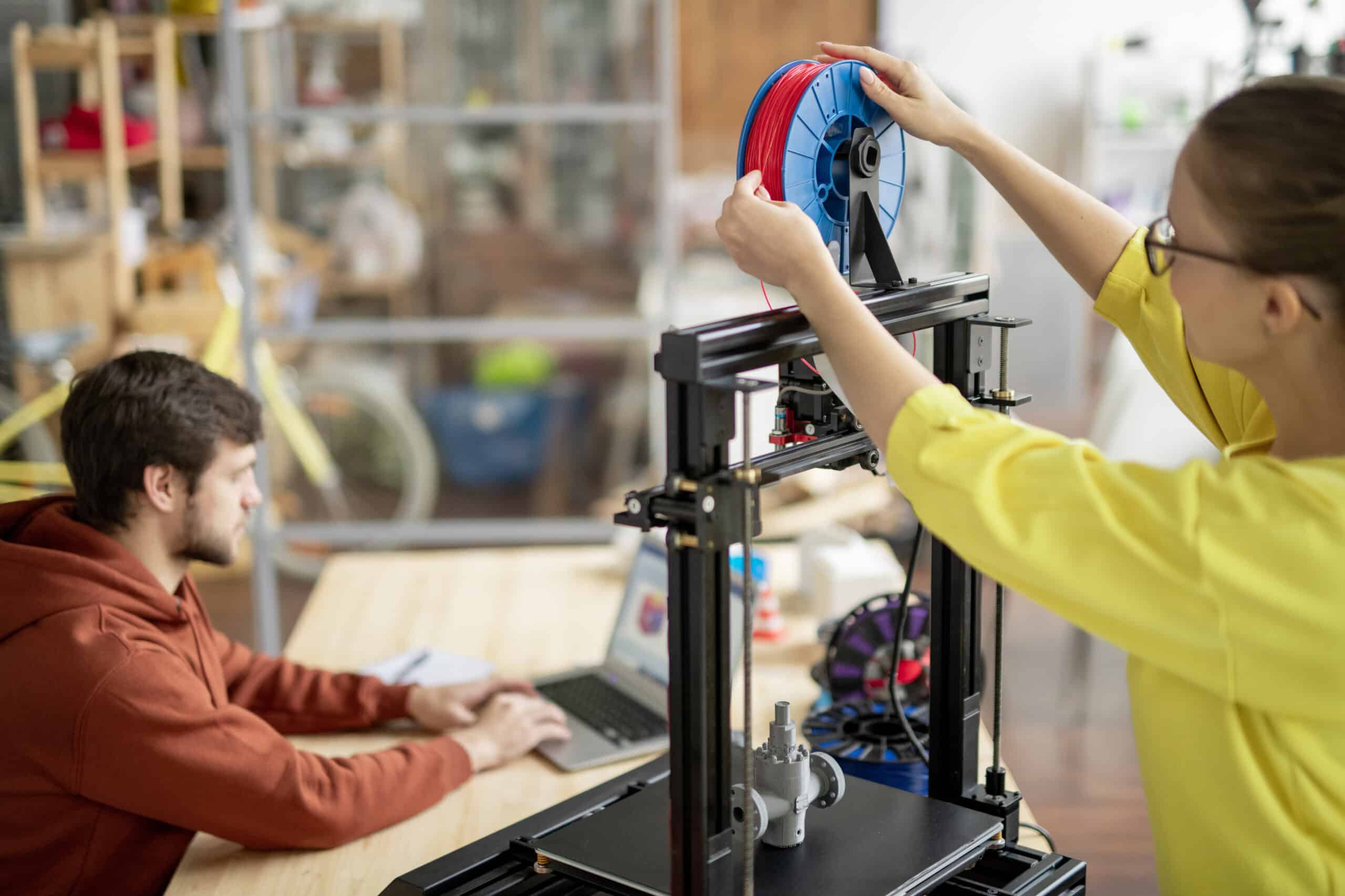 Person changing a filament spool on a 3D printer