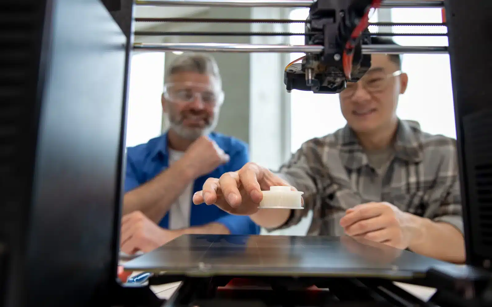 Engineers inspecting the extrusion process on a 3D printer