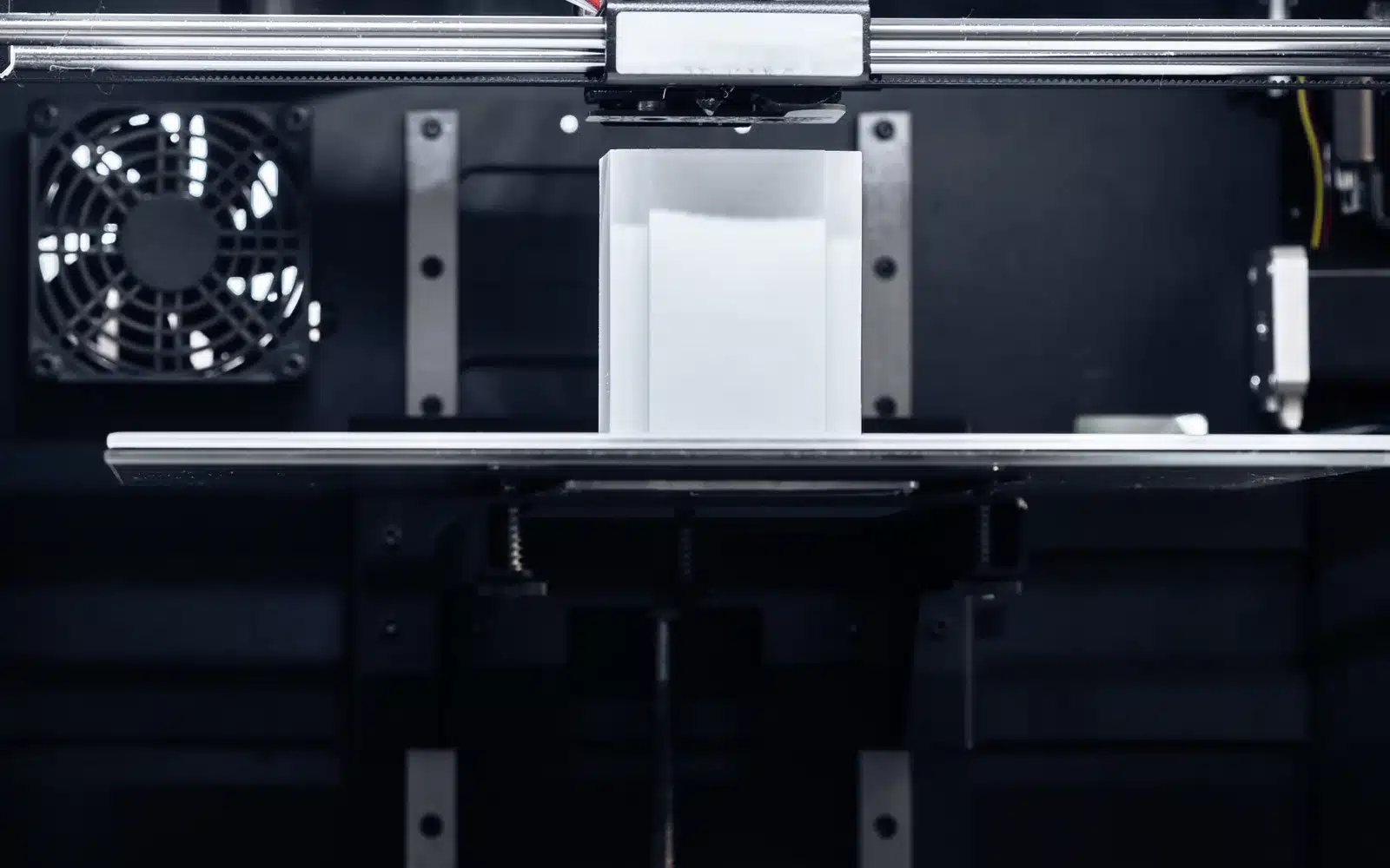 White plastic part being printed on an FDM machine
