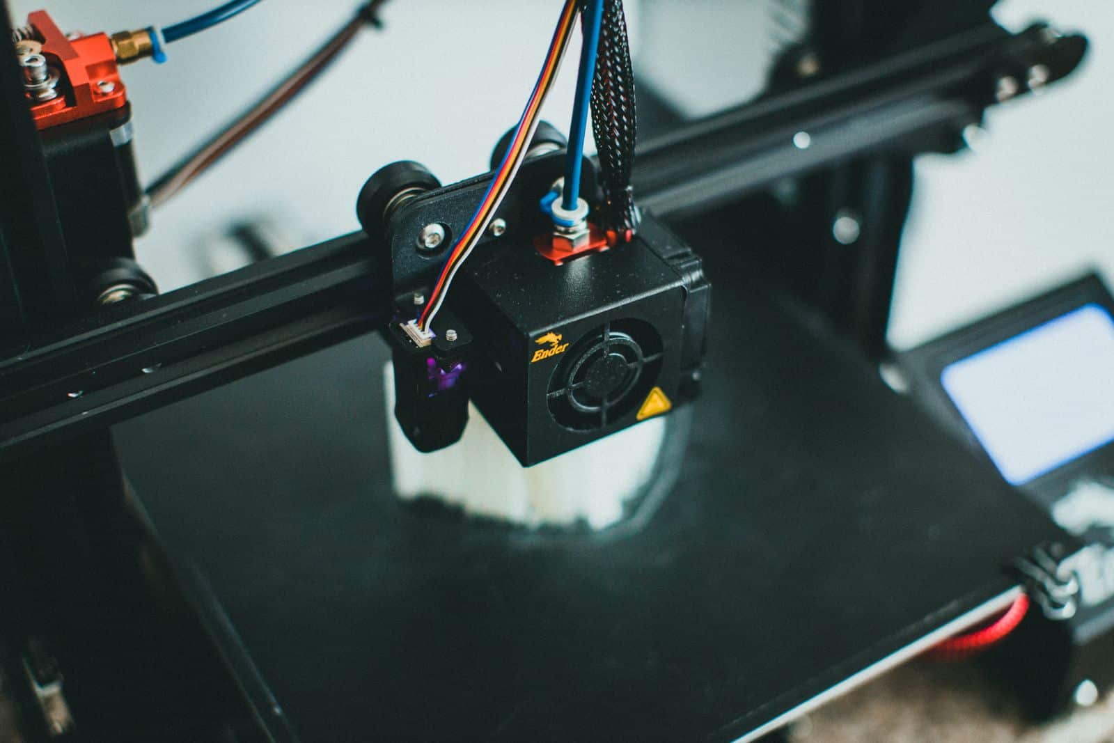 Detailed shot of a 3D printer creating an object, focusing on the cooling fan and print head