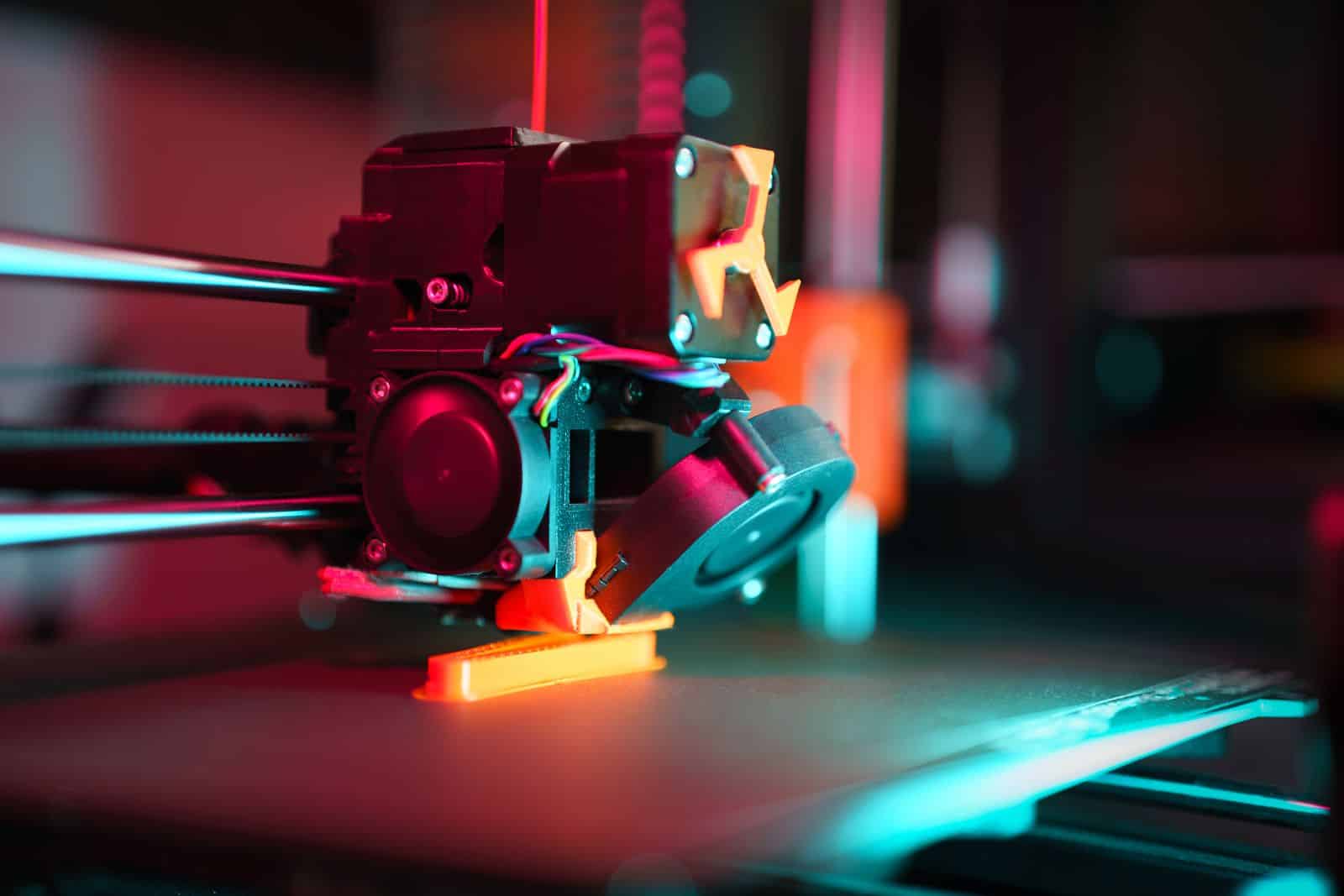 Close-up of a 3D printer in action with neon lighting, showcasing technology in prototyping