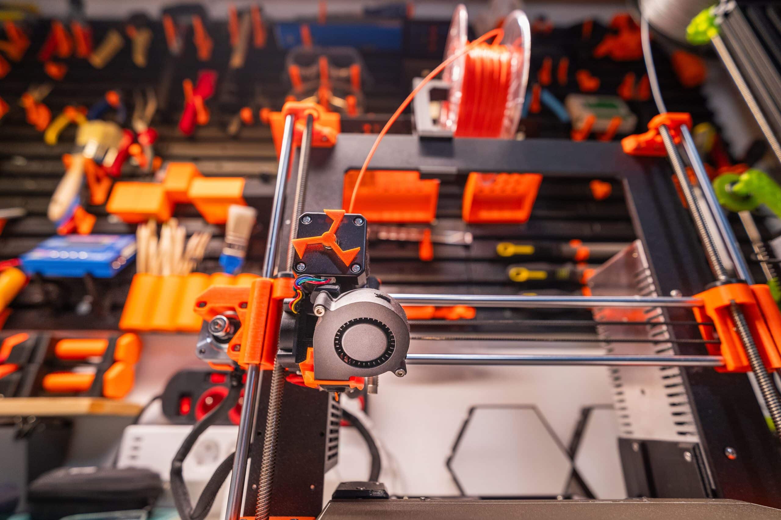 Detailed view of a 3D printer with filament and tools in a workshop setting