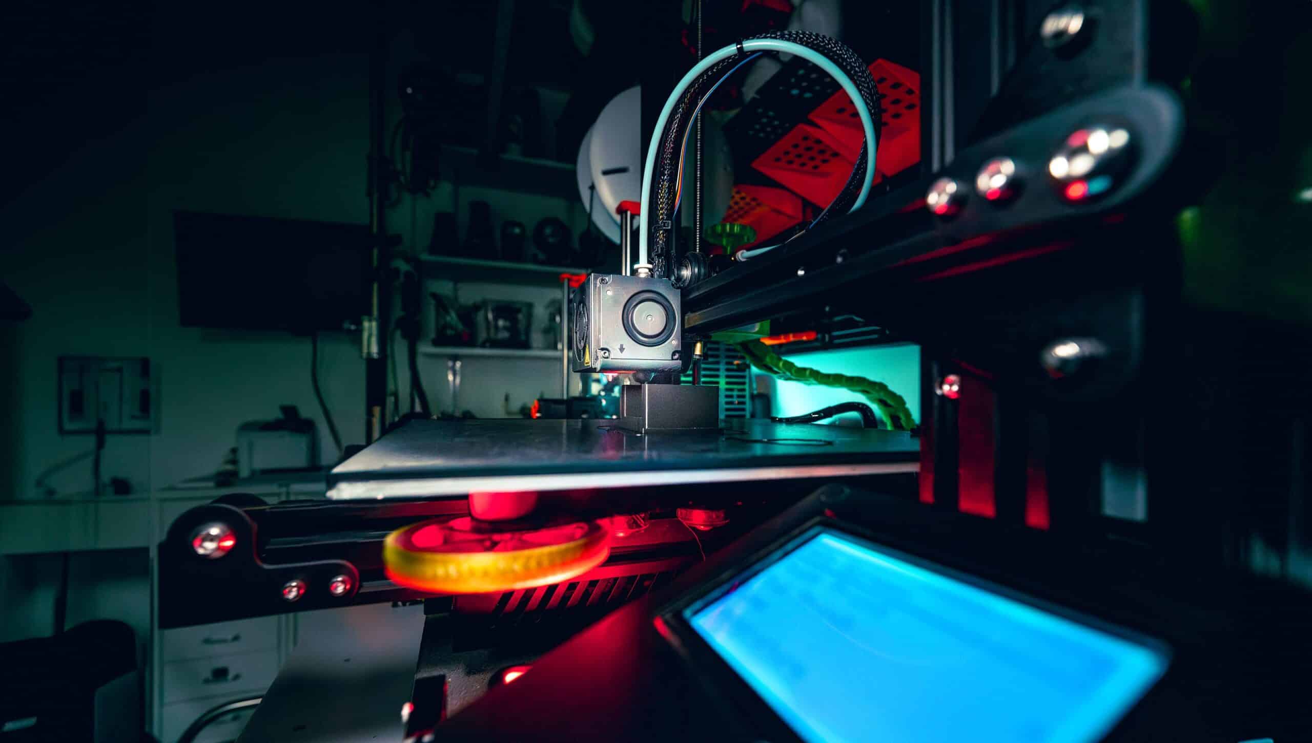 Detailed view of a 3D printer operating in a dimly lit workshop