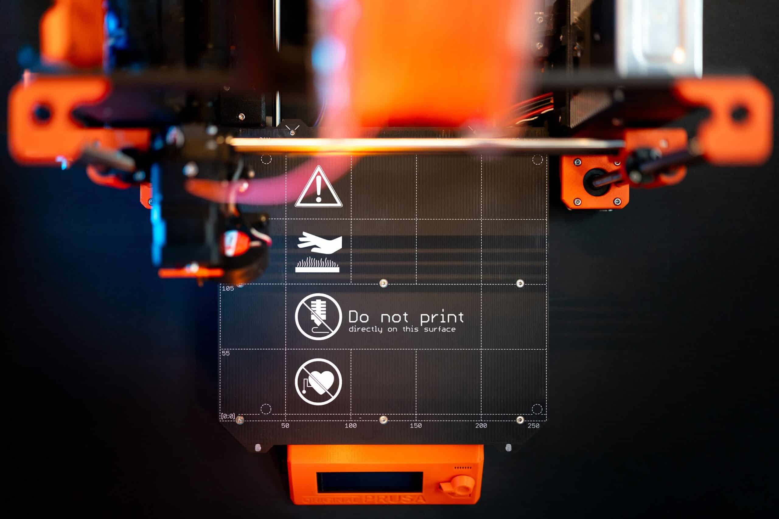 Detailed image of a 3D printer with caution signage, showcasing advanced manufacturing