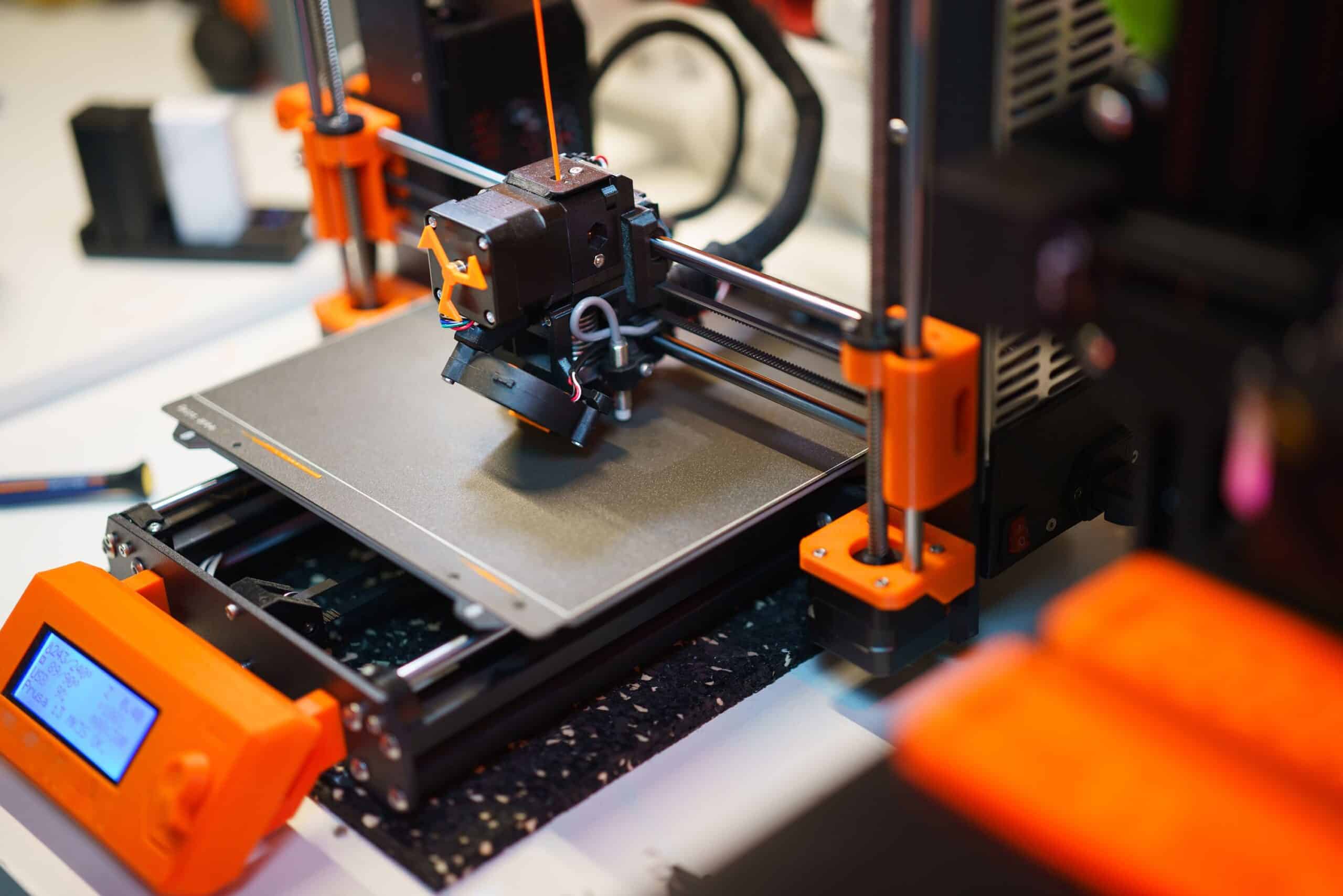 Detailed view of a 3D printer creating an object with orange components