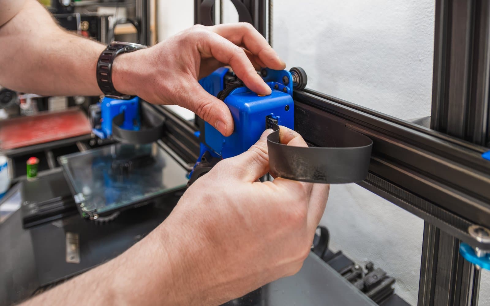 Close-up of hands performing maintenance on a 3D printer