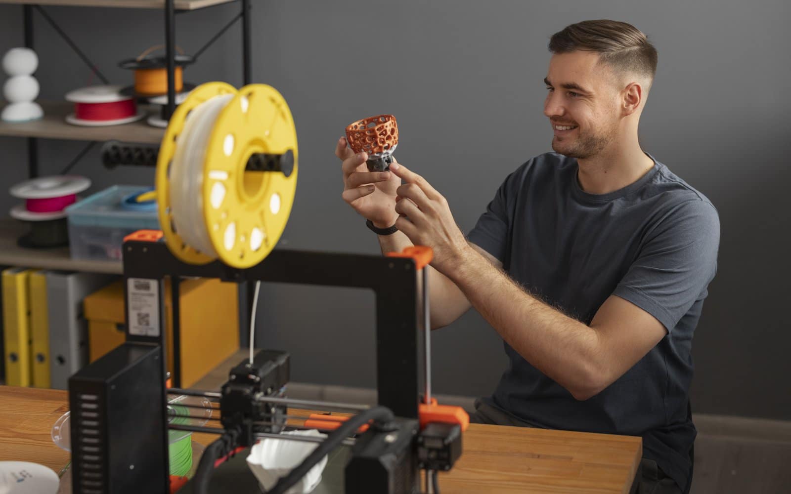 A person adjusting a desktop 3D printer while it operates.