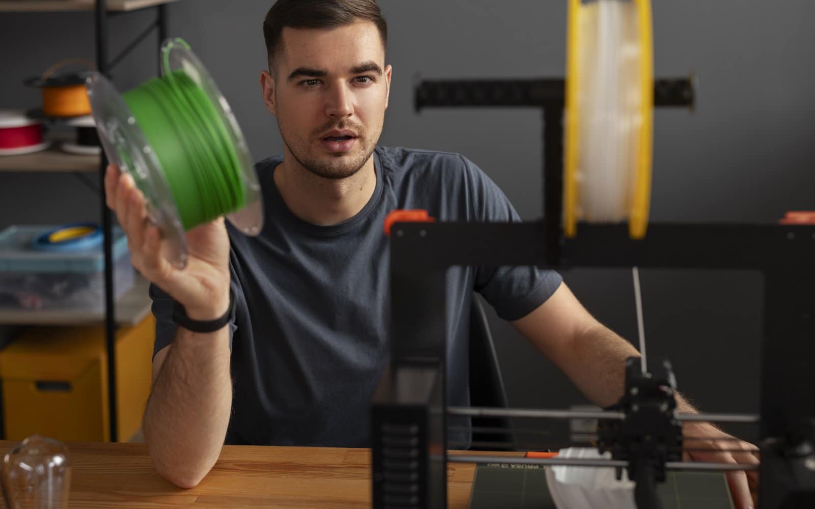 Person closely monitoring a 3D printer during an active print job.