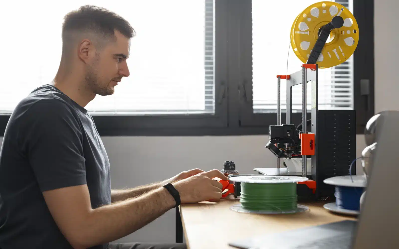 Designer monitoring a desktop 3D printer in a workshop
